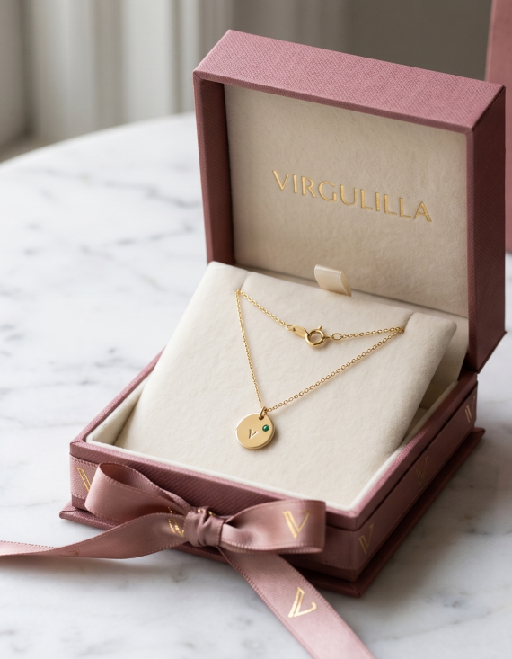 Caja de regalo de la marca Virguliilla abierta cuidadosamente, mostrando un collar fino de oro en su interior, lista para ser entregada.