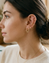 Primer plano del perfil de una mujer mostrando una combinación elegante de pendientes de oro de Virguliilla, incluyendo aros y pequeños puntos de luz en diferentes perforaciones de la oreja.